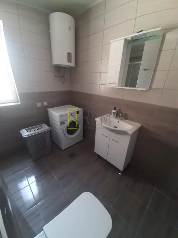 Moderno opremljeno kupatilo sa veš mašinom i bojlerom.