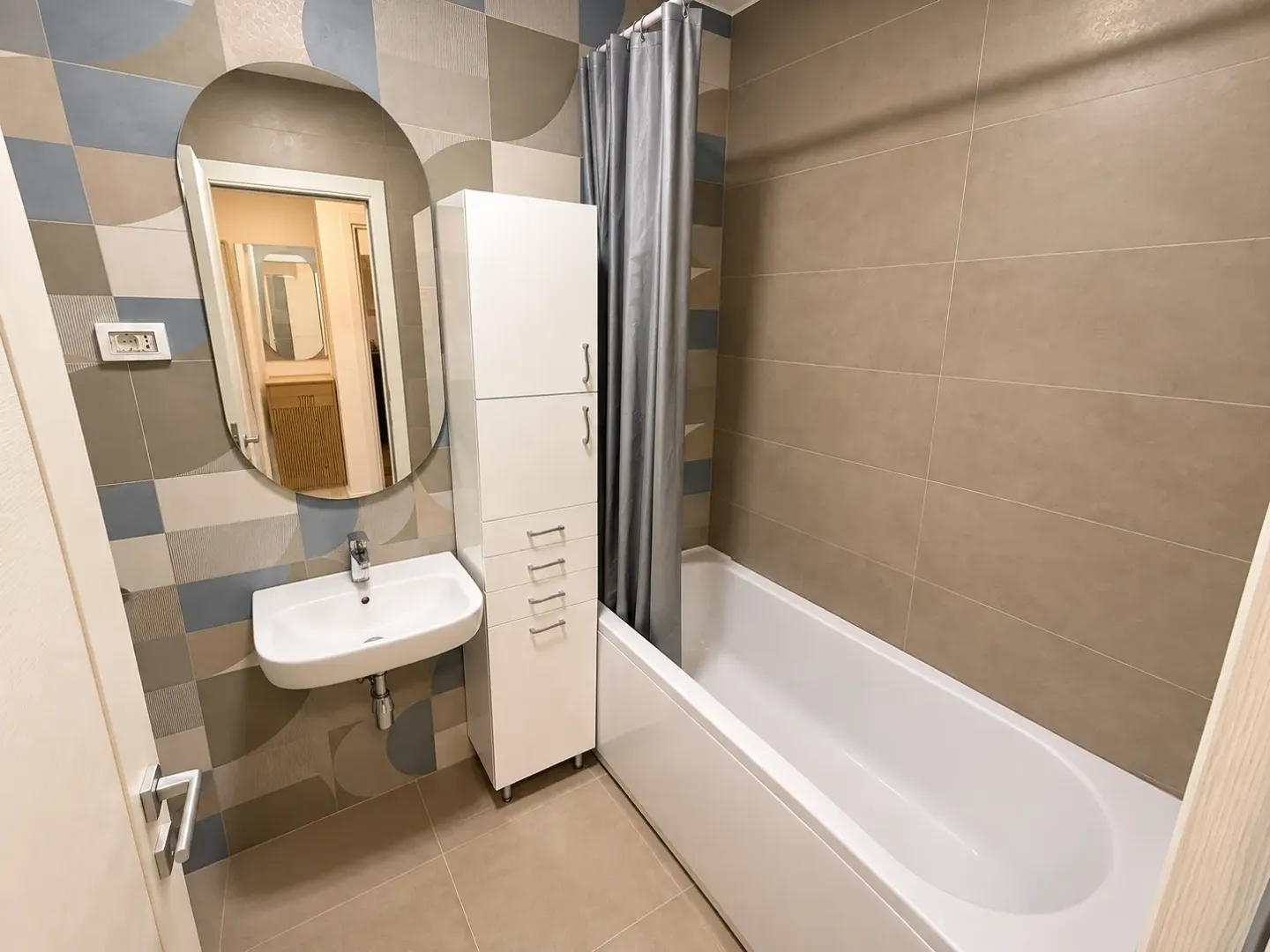 Modernly equipped bathroom with a bathtub, washbasin, and mirror.