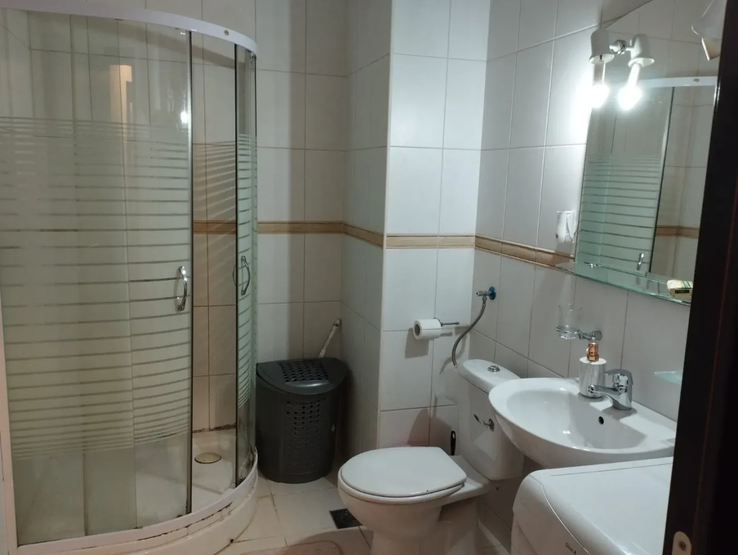 Jednostavno kupatilo sa tuš kabinom, lavaboom i toaletom.