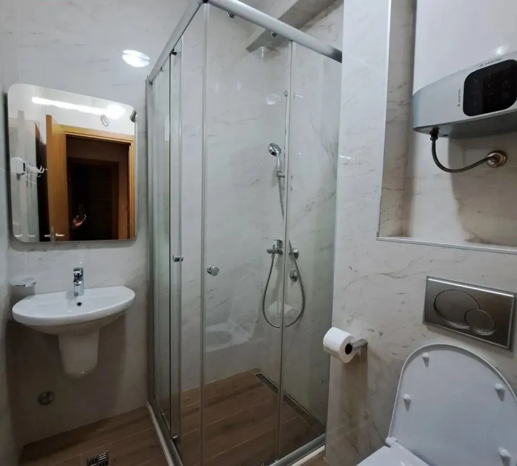 A modern equipped bathroom with a shower cabin, washbasin, and toilet.