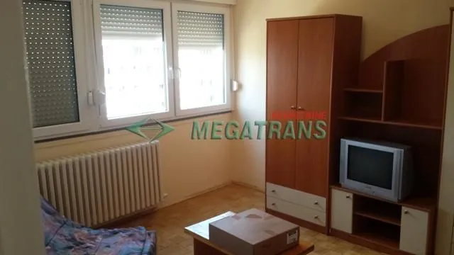 Dnevna soba sa drvenim nameštajem, televizorom i prozorima.