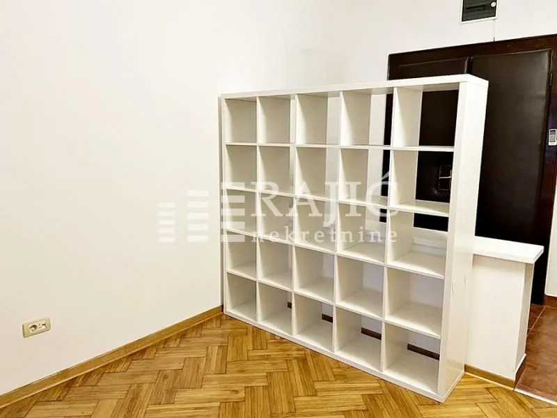 Living room with parquet flooring and a white room divider shelf.