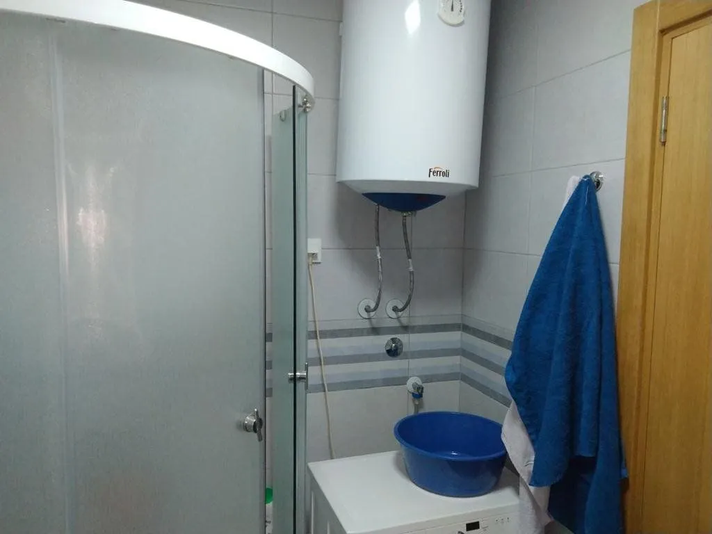 Bathroom with a shower cabin, water heater, and washing machine.