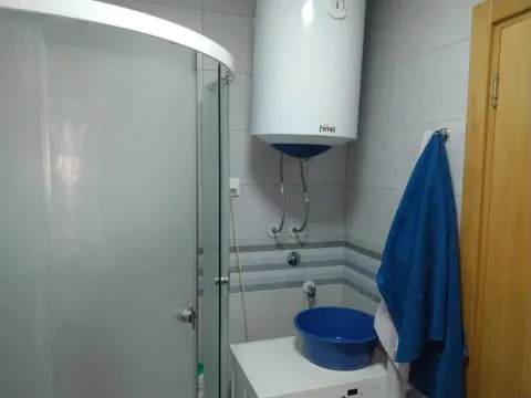 Bathroom with a shower cabin, water heater, and washing machine. - image 10