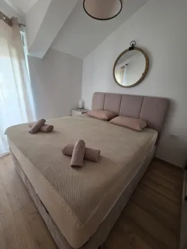 Furnished bedroom with a double bed, a round wall mirror, and laminate flooring. - image 7