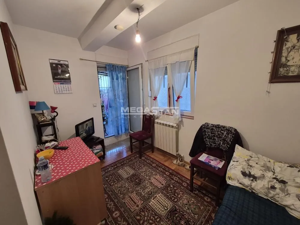Manja soba sa krevetom, radnim stolom i izlazom na terasu.