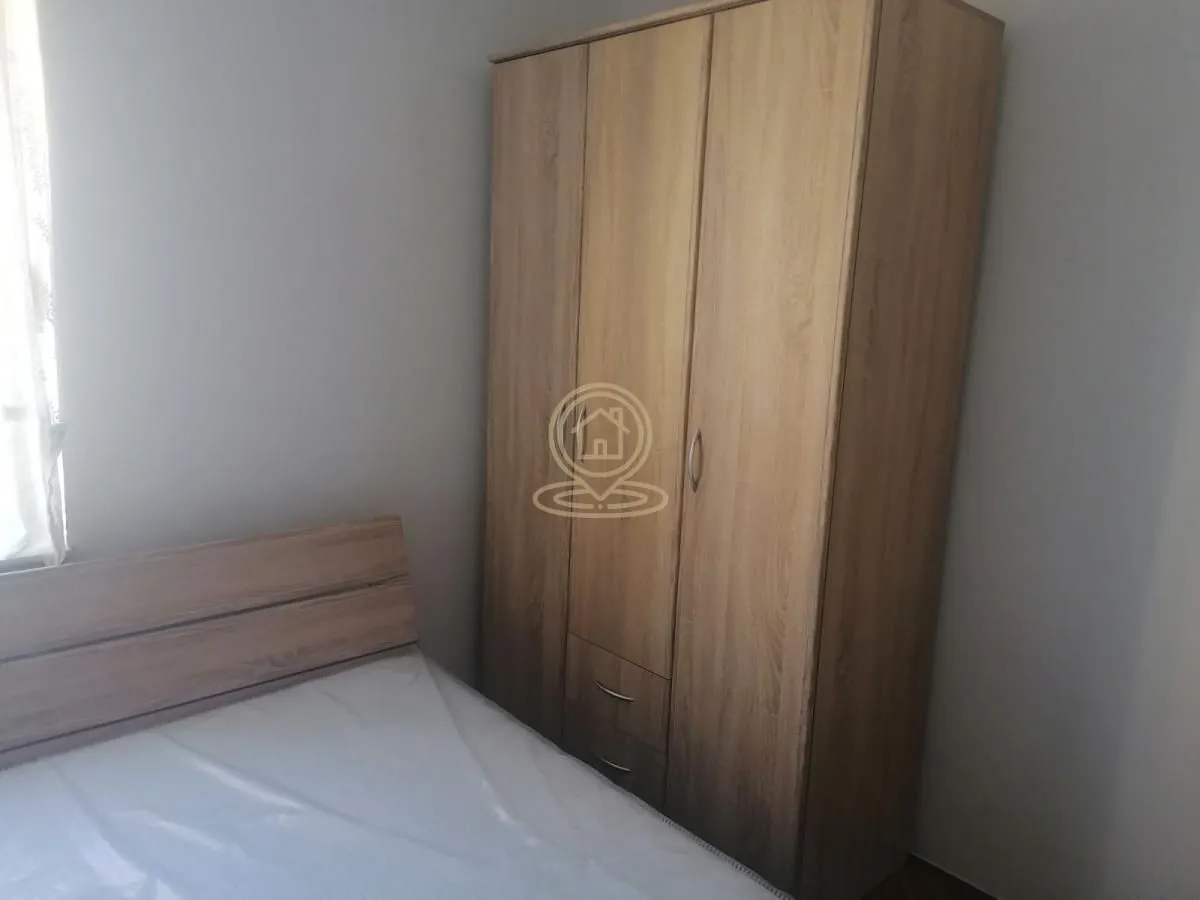 Spavaća soba sa bračnim krevetom i drvenim ormanom.