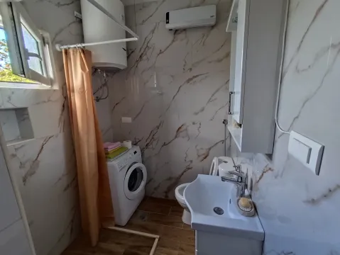 Kupatilo opremljeno umivaonikom, veš mašinom i tuš kabinom sa zavjesom. - image 11