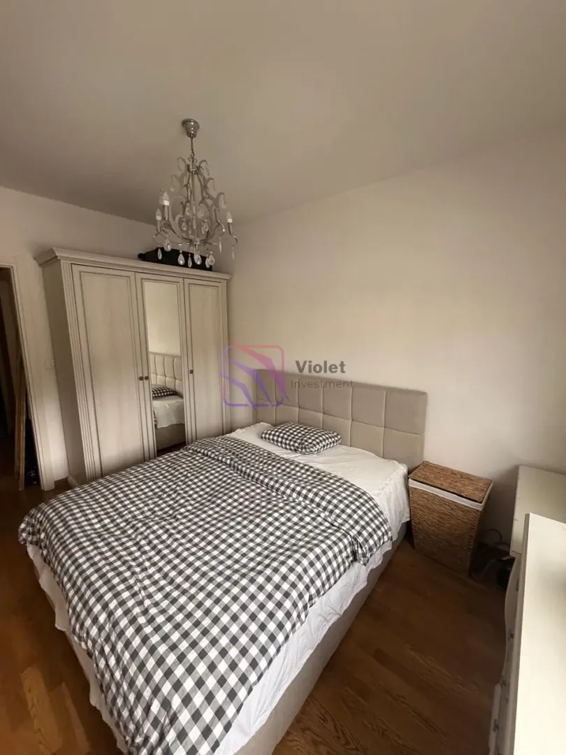 Namještena spavaća soba sa bračnim krevetom, ormarom i lusterom.
