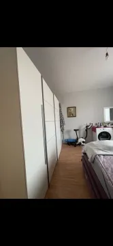 Spavaća soba sa velikim bijelim garderoberom, krevetom i kućnim biciklom. - image 15