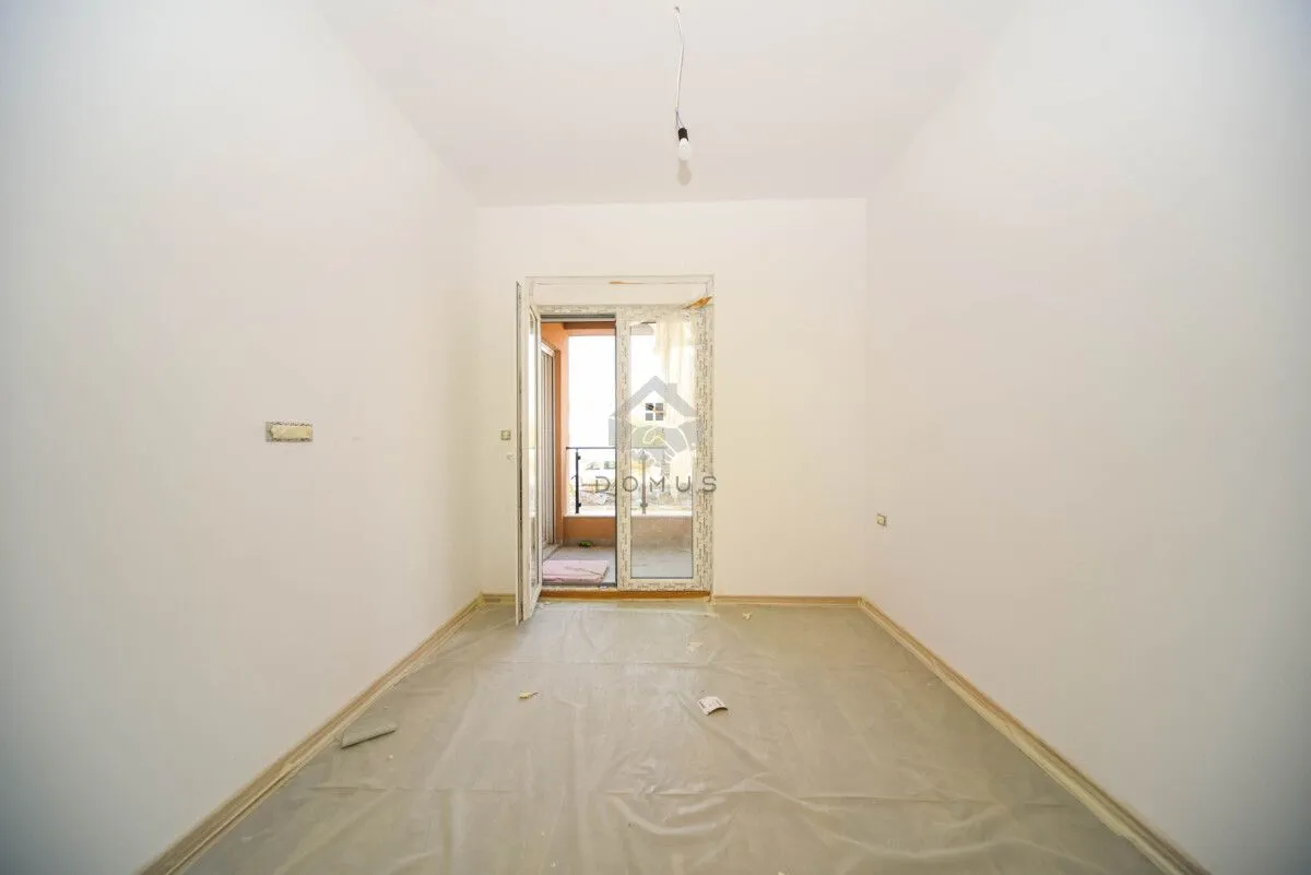 Prazna neuređena prostorija sa balkonskim vratima i podom prekrivenim zaštitnom folijom.