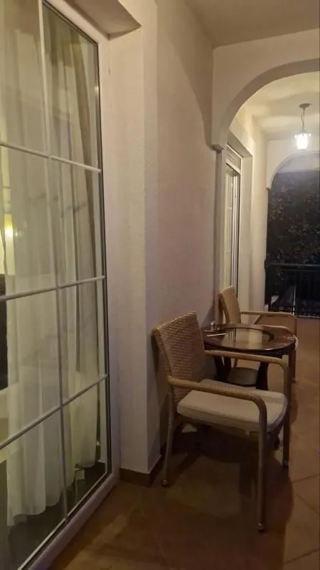 Covered terrace furnished with rattan chairs and a small table.