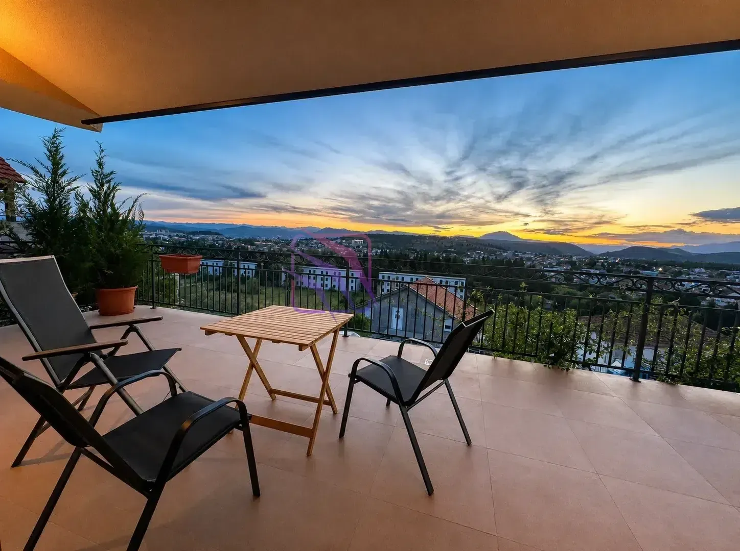 Unfurnished terrace with seating furniture and a city view at dusk.