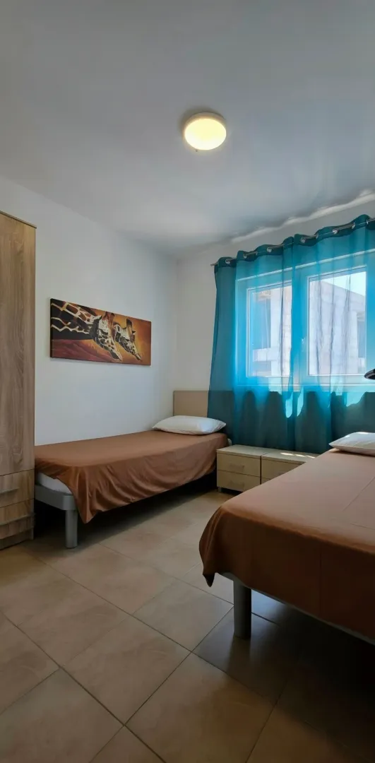 Namještena spavaća soba sa dva kreveta i ormarom.