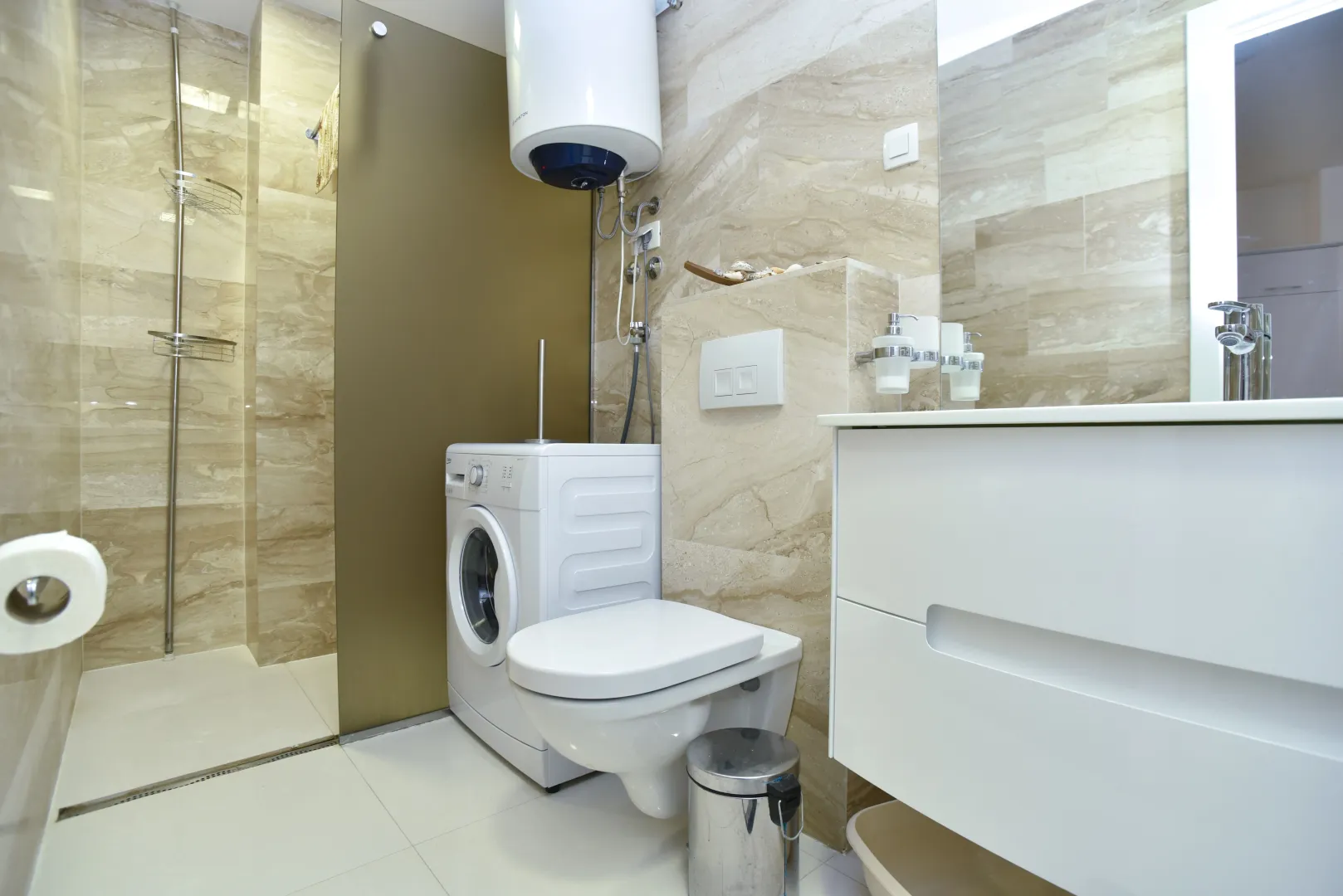Modernly equipped bathroom with a shower cabin, toilet, and washing machine.
