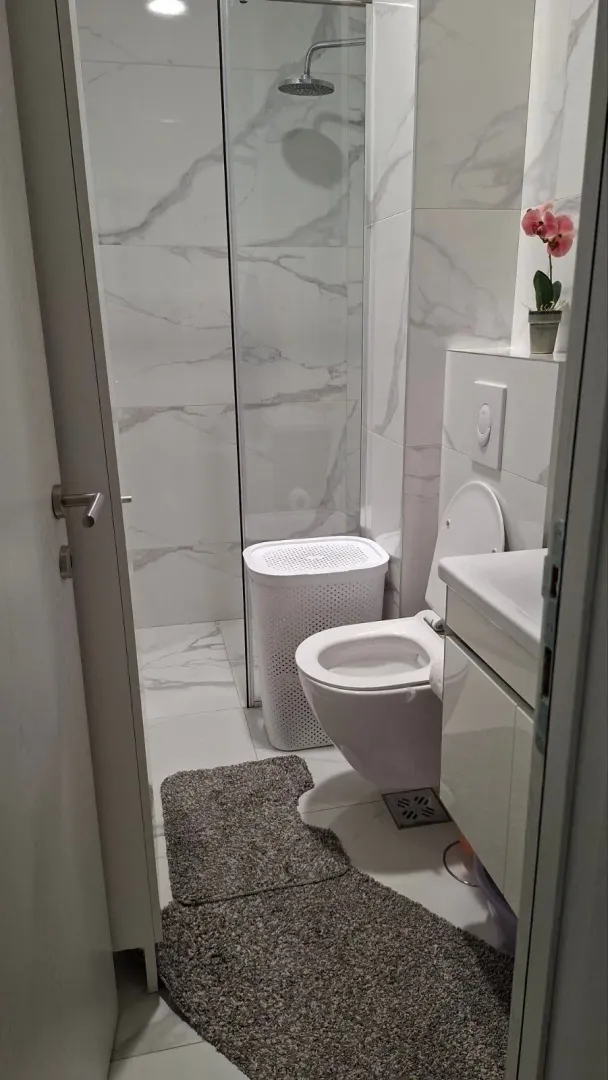 Moderne kupatilo sa tuš kabinom, umivaonikom i toaletom.