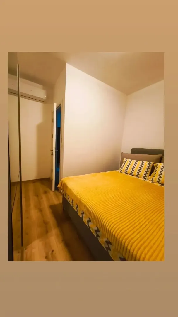 Spavaća soba sa bračnim krevetom i drvenim podom.