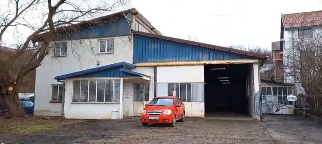 Exterior view of the commercial building with a warehouse space and a parked car.