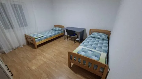 Spavaća soba sa dva drvena kreveta i radnim stolom. - image 2