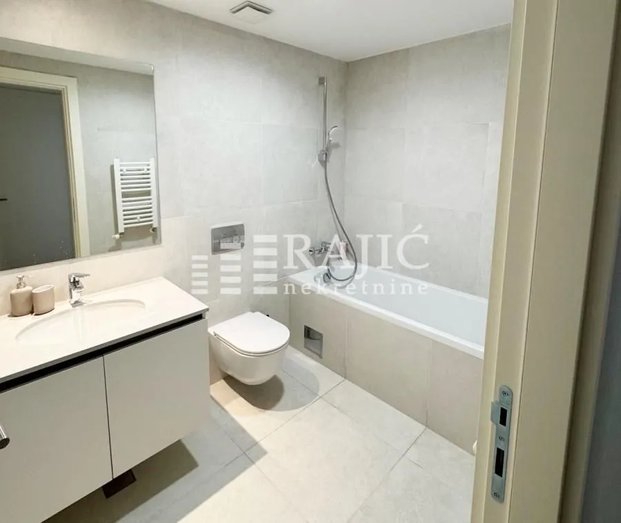 Modernly equipped bathroom with a bathtub, washbasin, and toilet.