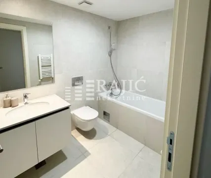 Modernly equipped bathroom with a bathtub, washbasin, and toilet. - image 17
