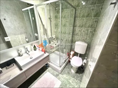 Bathroom equipped with a washbasin, shower cabin, and toilet. - image 3
