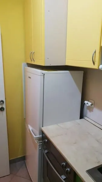 Small kitchen with a refrigerator and yellow cabinets.