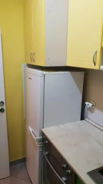 Small kitchen with a refrigerator and yellow cabinets. - image 19