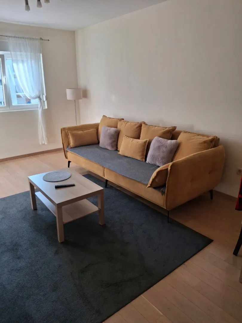 Bright living room with a yellow sofa, coffee table, and rug.
