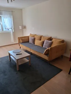 Bright living room with a yellow sofa, coffee table, and rug. - image 2