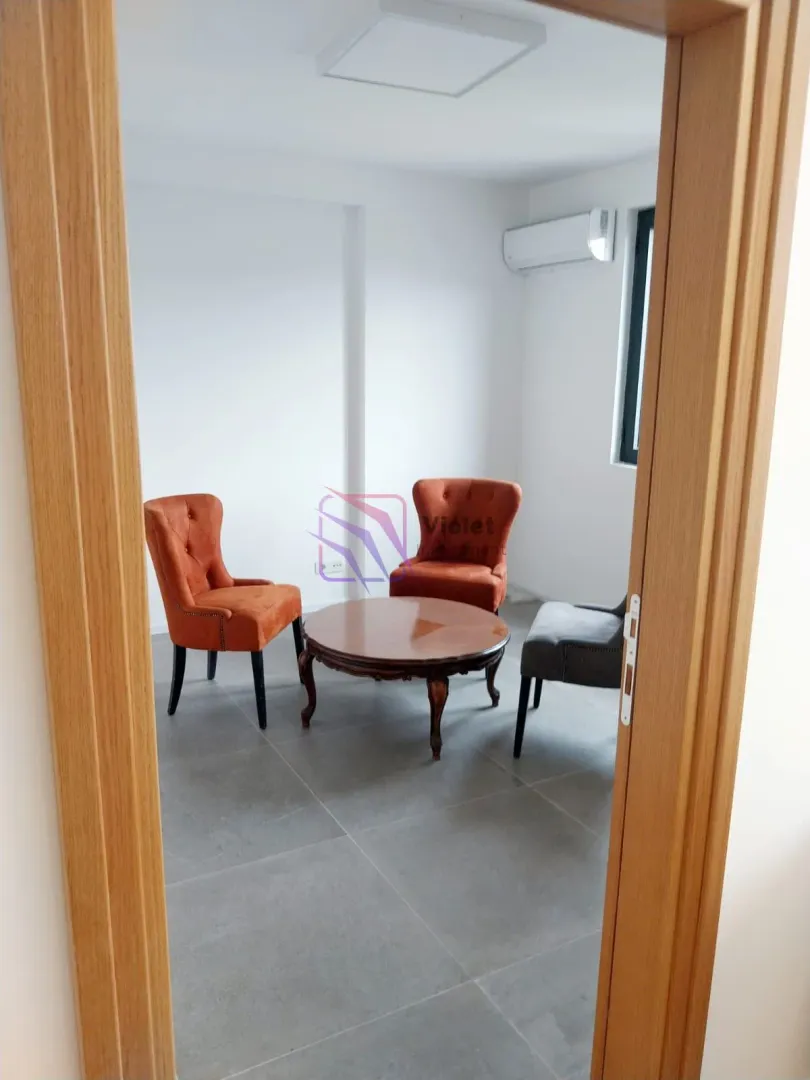Small room with armchairs and a coffee table seen through an open door.