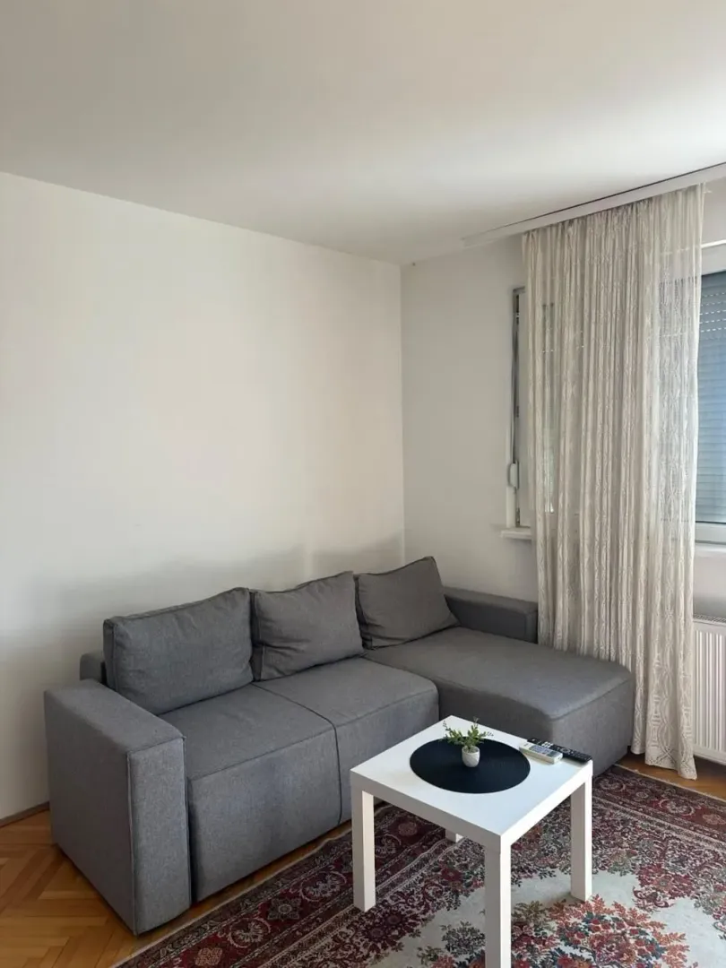 Corner sofa in the living room with a small coffee table and a window.