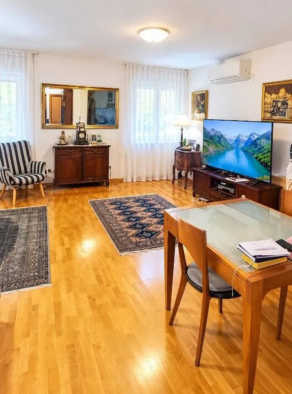 Prostrani dnevni boravak sa trpezarijskim stolom, TV-om i parketom.