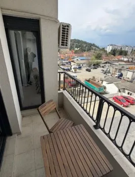 Manji balkon sa drvenim stolom, stolicom i pogledom na okolinu. - image 7