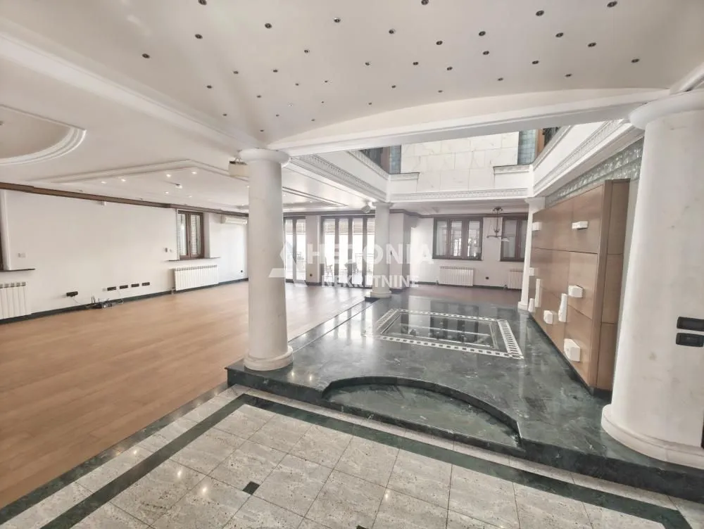 Spacious bright living room with columns and a dropped ceiling with lighting.