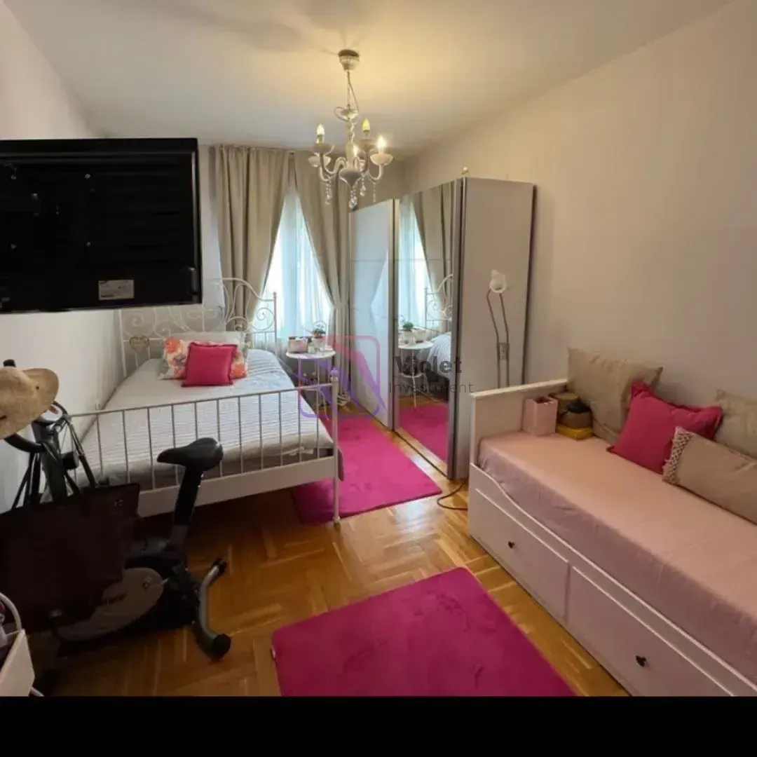 Spavaća soba sa krevetom, garderoberom, kaučem i televizorom na zidu.