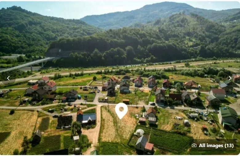 Pogled iz vazduha na zemljište i kuće u zelenom okruženju.