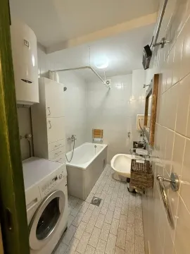 Small bathroom with a bathtub, sink, and washing machine. - image 11