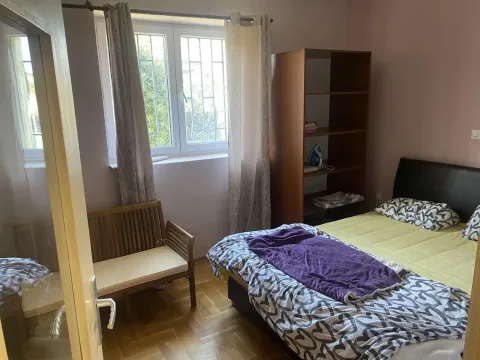 Jednostavno namještena spavaća soba sa bračnim krevetom, drvenom policom i prozorom. - image 3