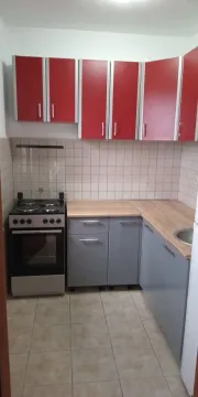 Small kitchen with red and grey cabinets and a stove. - image 3