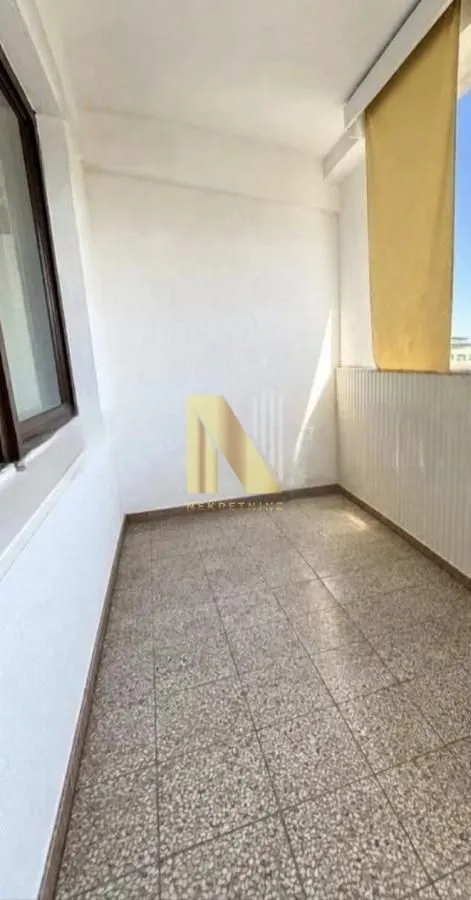 Prazna natkrivena terasa sa popločanim podom i prozorom.