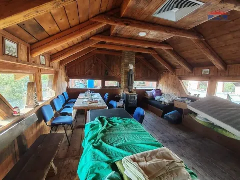 Wood-paneled attic interior with a seating area and a dining table. - image 3