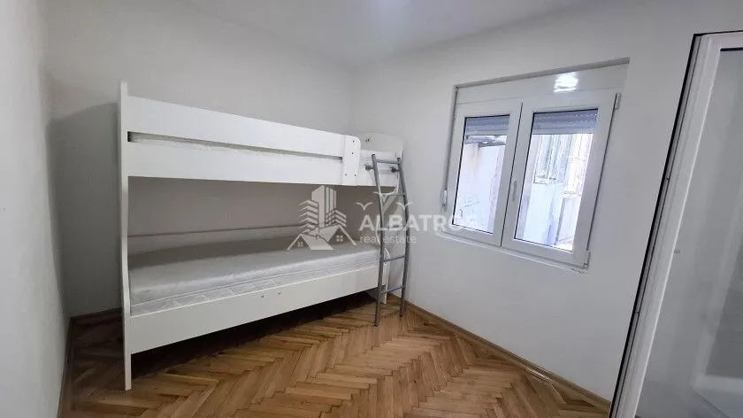 Spavaća soba sa bijelim krevetom na sprat i drvenim parketom.
