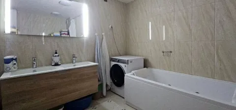 Bathroom equipped with a vanity unit, bathtub, and washing machine. - image 3