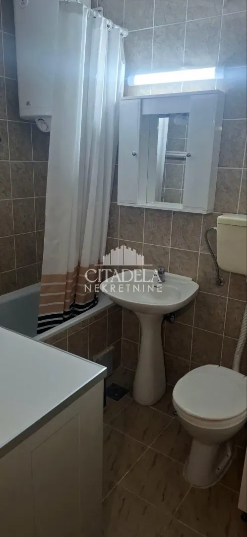 Smaller bathroom with a bathtub, washbasin, toilet, and mirrored cabinet.