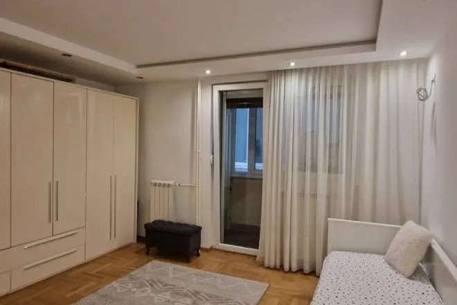 Nameštena spavaća soba sa velikim garderoberom, krevetom i izlazom na terasu.