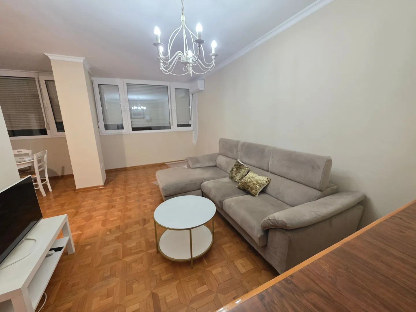 Prostrana dnevna soba sa garniturom za sjedenje i parketom.