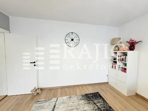Bright living room with white furniture and wooden flooring.