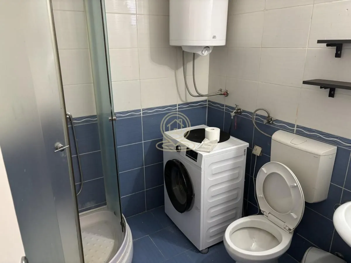 Bathroom equipped with a shower cabin, toilet, washing machine, and water heater.