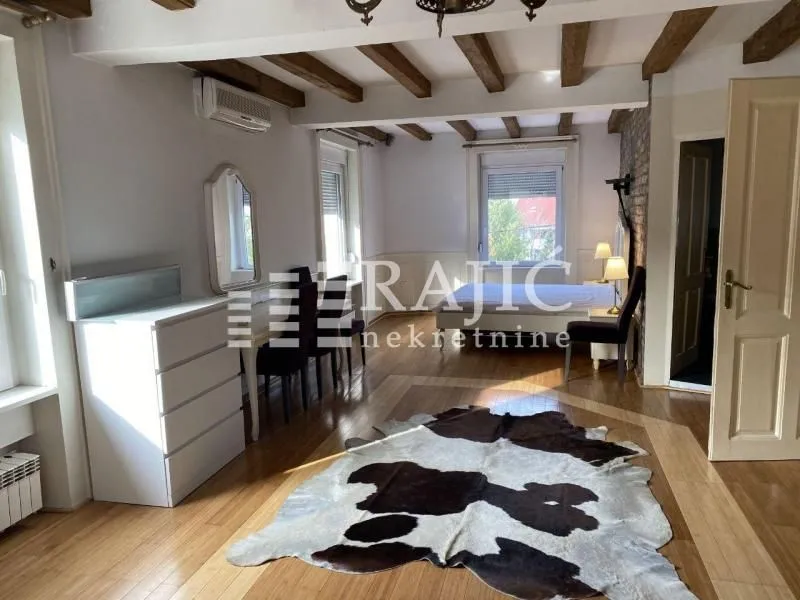 Spacious bedroom with wooden ceiling beams and parquet flooring.